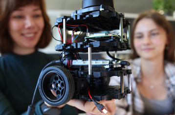 [Translate to English:] Zwei Personen betrachten einen Roboter