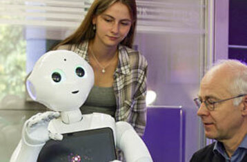 Studentin und Professor agieren mit humanoidem Roboter