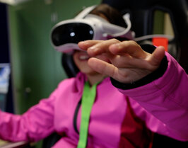 Ein Mädchen sitzt und hat dabei eine VR-Brille auf