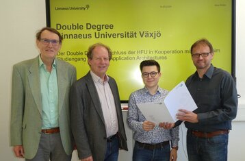 Vier Herren der zweite von rechts hält eine Auszeichnung in der Hand