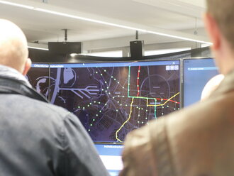 Zwei Menschen schauen auf ein Display mit Verkehrslinien