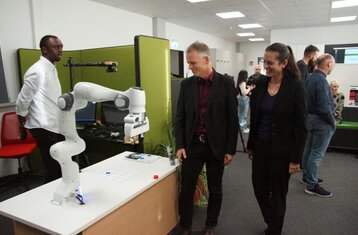 Zwei Personen schauen sich an einem Stand einen Roboterarm an