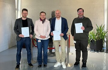 Four people looking at the camera and holding certificates