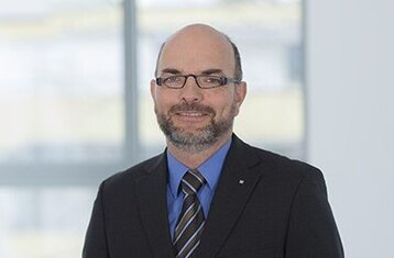 Man sieht Werner Riedel im Anzug im Profil