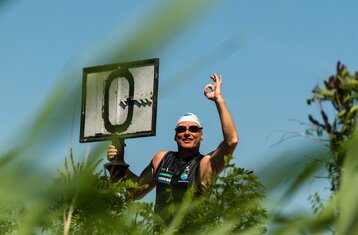 Ein Mann zeigt Okay und hält in der anderen Hand eine Art Schild mit einer Null