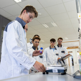 Menschen im Labor mit Laborkitteln wiegen etwas ab