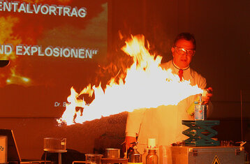 Vortragender hinter einer Stichflamme, zu Demonstrationszwecken eingesetzt