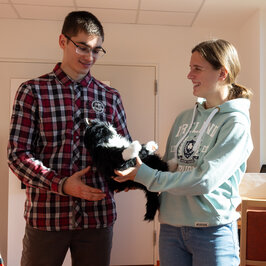 Ein junger Mann bekommt eine Roboterkatze von einer jungen Dame überreicht