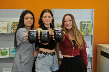 three students are holding coffee mugs