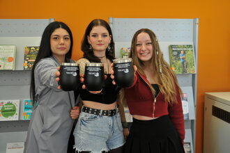 three students are holding coffee mugs