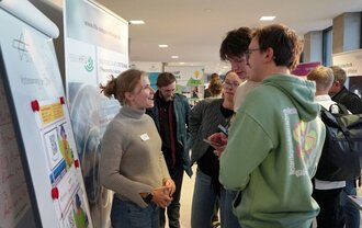 Eine Gruppe von Menschen, die an einem Messestand sprechen