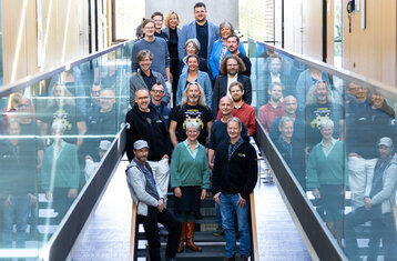 Eine Menschengruppe steht auf einer Treppe im Mediengebäude