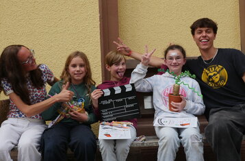 drei Kinder und zwei Erwachsene auf einer Bank zeigen die Auszeichnung