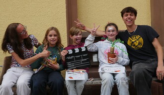 drei Kinder und zwei Erwachsene auf einer Bank zeigen die Auszeichnung