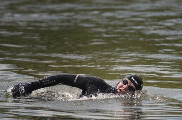 Man sieht einen Mann im Neoprenanzug und mit Taucherbrille beim Schwimmen