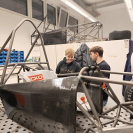 Zwei Personen unterhalten sich neben dem Rennwagen