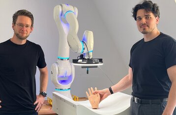Two scientist showing model of hand and robot arm