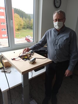 Prof. Dr. Stephan Lambotte is seen standing in front of a table with a device