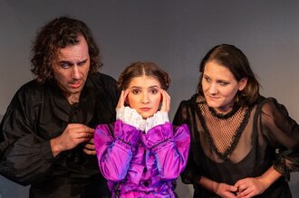 Drei Schauspieler zwei Frauen ein Mann, die Frau in der Mitte trägt pink