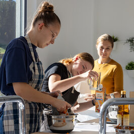 Eine Frau beobachtet zwei Mädchen beim Abmessen von Zutaten