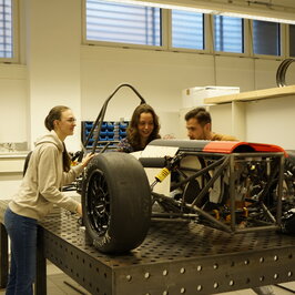 Drei Studierende an dem Automodell