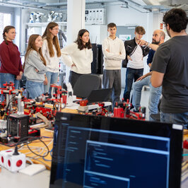 Eine Gruppe im Halbkreis hört einem Vortrag zu