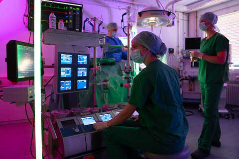 Drei Personen im OP-Saal mit Herz-Lungen-Maschine