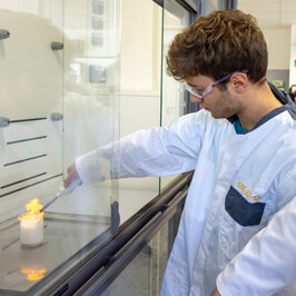 Ein junger Mann im Laborkittel zündet etwas an und es gibt eine große Flamme