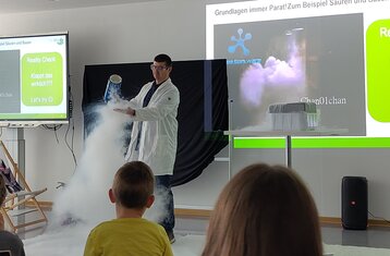 Ein Mann in Laborkittel demonstriert weißen "Nebel"