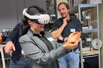 Drei Personen, eine davon trägt eine VR Brille