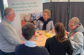 Menschen betrachten am Ausstellungsstand das große Holzboard