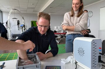 A person reaches into a container of ice water and a measurement is taken