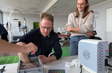 Eine Person fasst in ein Gefäß mit Eiswasser, es findet eine Messung statt