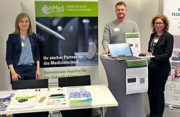 Three people at a project stand