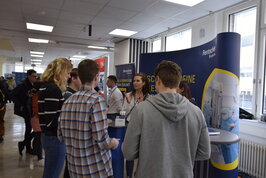 Eine Frau beim Stand der Firma Rentschler spricht mit einer Gruppe Studierender