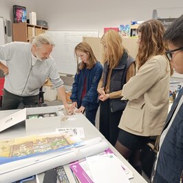 Ein professor zeigt einer Gruppe ein Brettspiel , das Studierende entwickelten