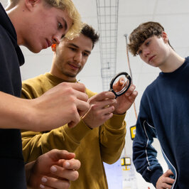 Drei junge Männer versuchen mit einem Dietrich ein paar Handschellen zu öffnen