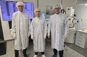 Three people wearing white coats in a lab