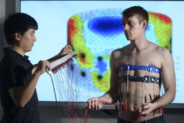 You see a shirtless man who has been wired up.