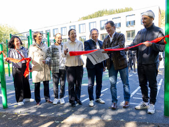 Eine Menschengruppe, die gemeinsam ein rotes Band zerschneidet