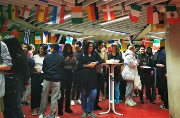 Symbolic image: The packed event room with guests and flags on the ceiling