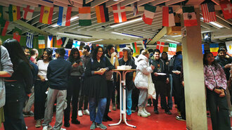 Symbolbild: Der volle Veranstaltungsraum mit Flaggen an der Decke und Gästen