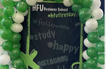 Man sieht einen Luftballonbogen um eine Kreidetafel, darauf stehen Hashtags