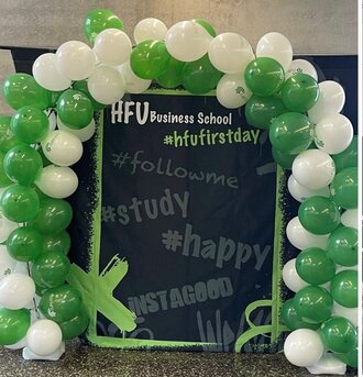 Man sieht einen Luftballonbogen um eine Kreidetafel, darauf stehen Hashtags