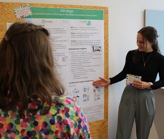 Eine Frau erklärt eine Posterwand