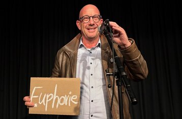 Prof. Selke holds a sign in his hand with the word “Euphoria” written on it.