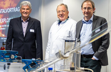 Gruppenbild mit drei Personen hinter einem Versuchsaufbau