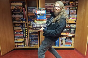 Symbolbild: Der Referatsleiter balanciert einen Stapel Brettspiele