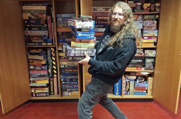 Head of the Games Club balancing a pile of board games