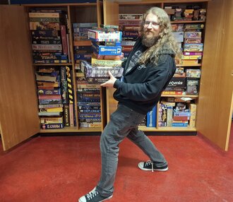 Head of the Games Club balancing a pile of board games